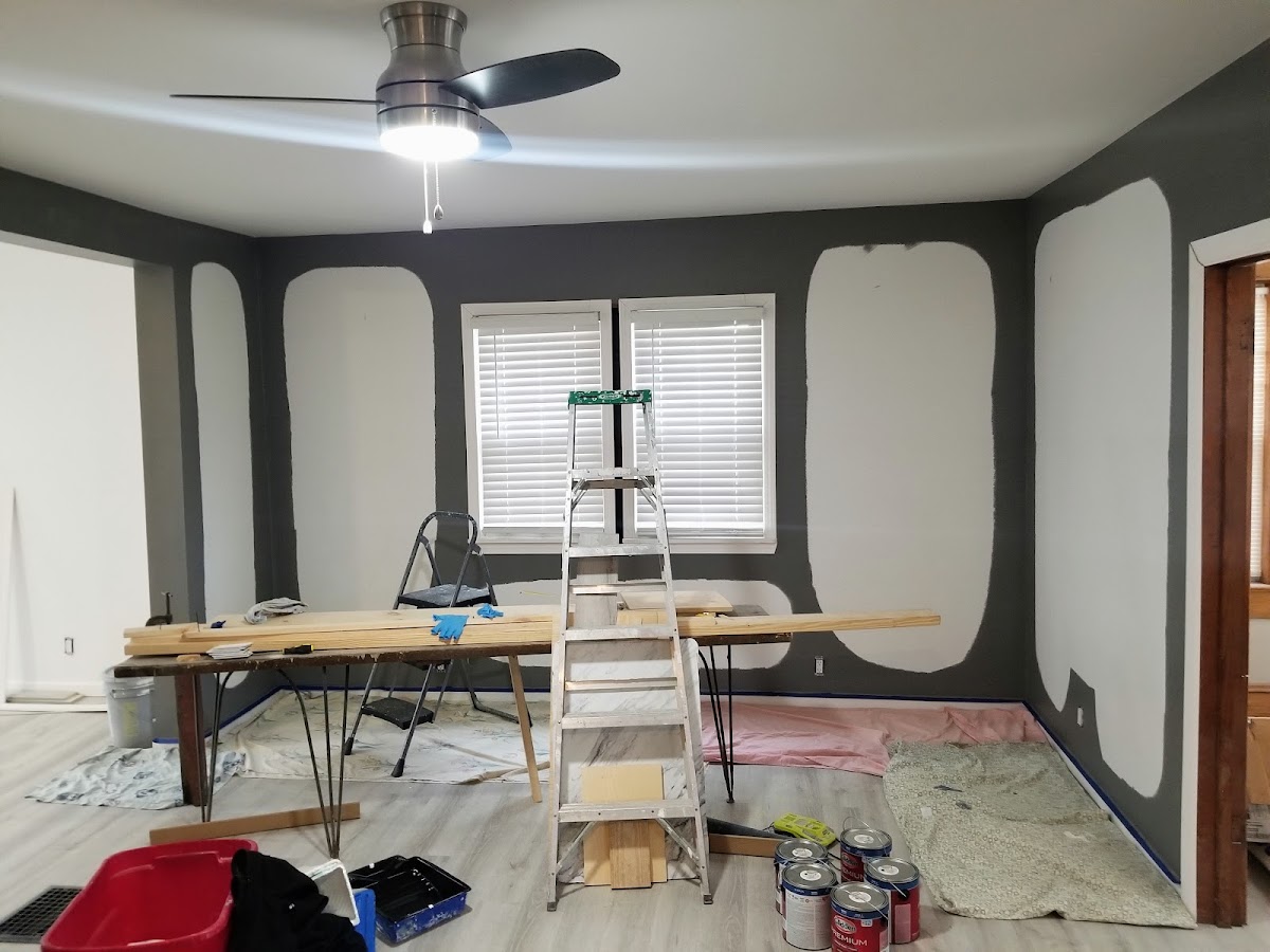 Dark grey walls being cut in with ladder and paint cans